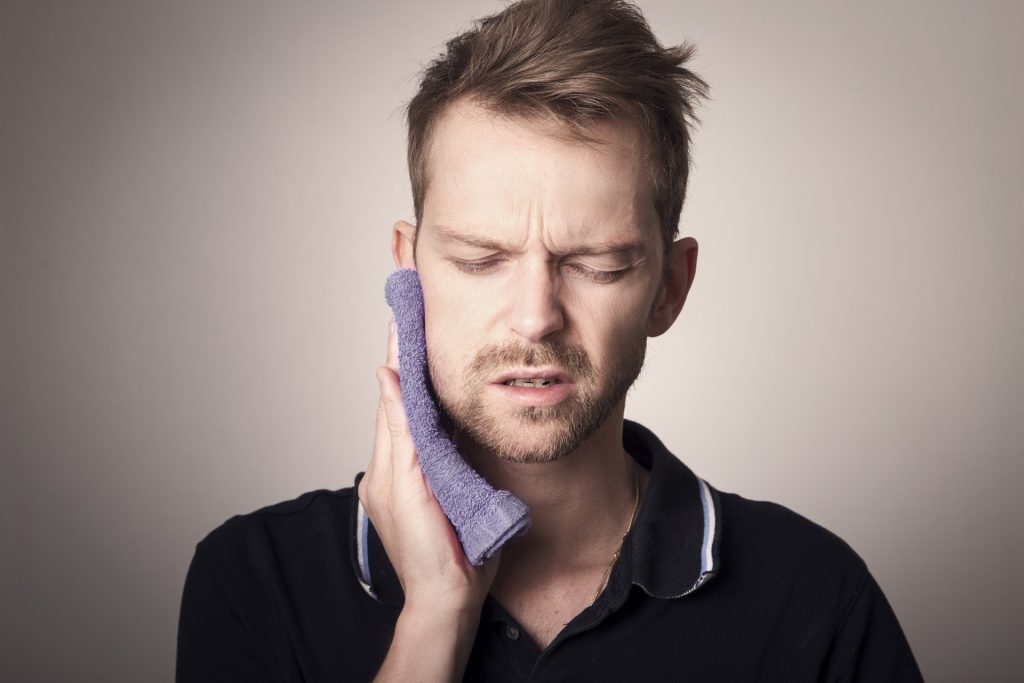 Man holding a towel on his mouth in pain