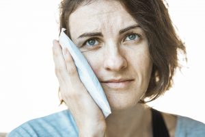 Woman holding a cold compress to her mouth
