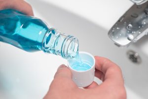 an individual pouring their mouthwash into the cap