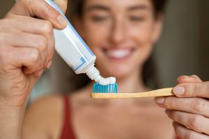 woman putting toothpaste on her toothbrush to brush her teeth with