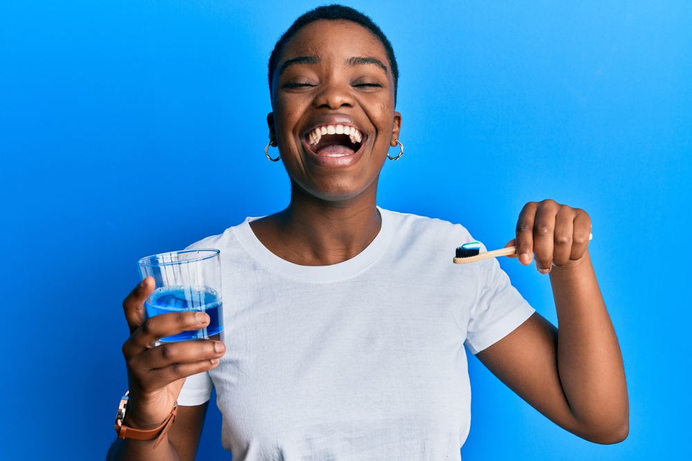 young woman holding her toothbrush and mouthwash