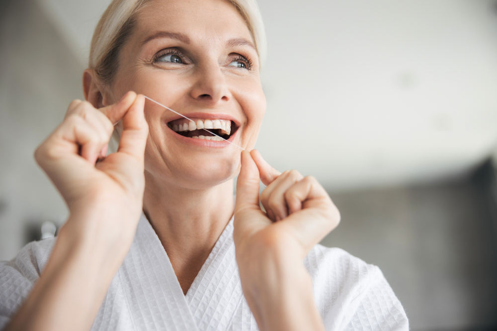 a blonde woman flossing her teeth