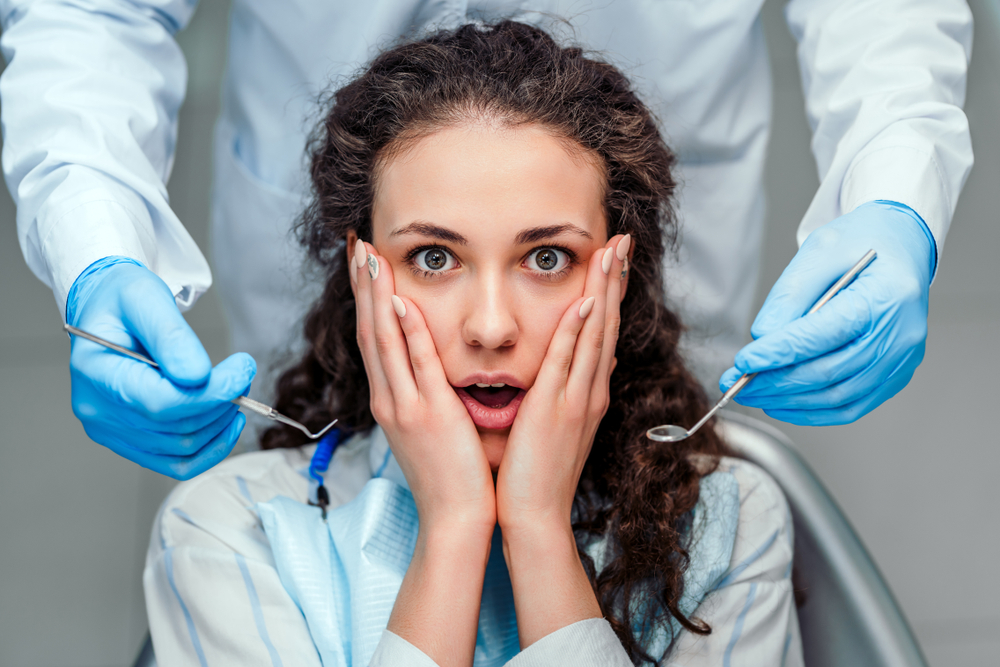 young woman looking shocked at the dentist
