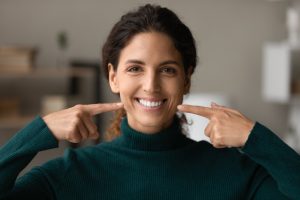 young woman pointing at her sparkling clean smile