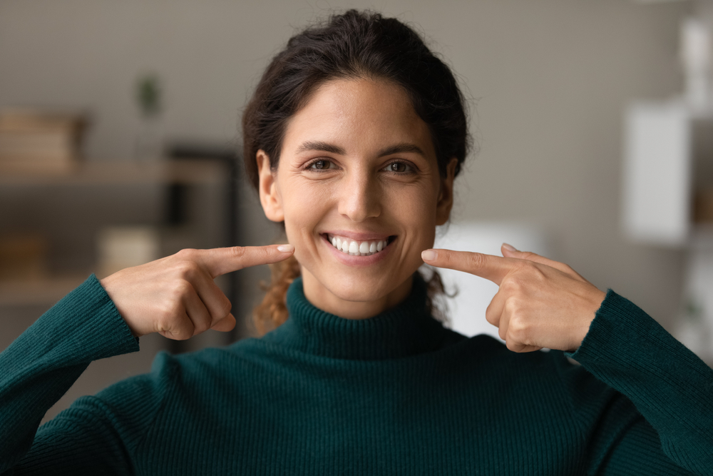 young woman pointing at her sparkling clean smile