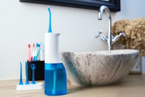 a waterpik and other oral hygiene products sitting bit a sink