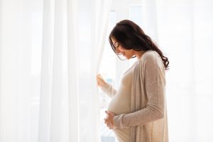 pregnant woman embracing her belly and smiling