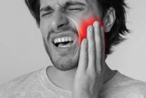 man holding the side of his cheek from tooth pain