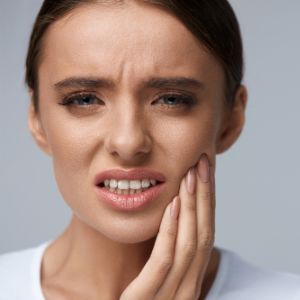 woman holding her cheek from tooth pain