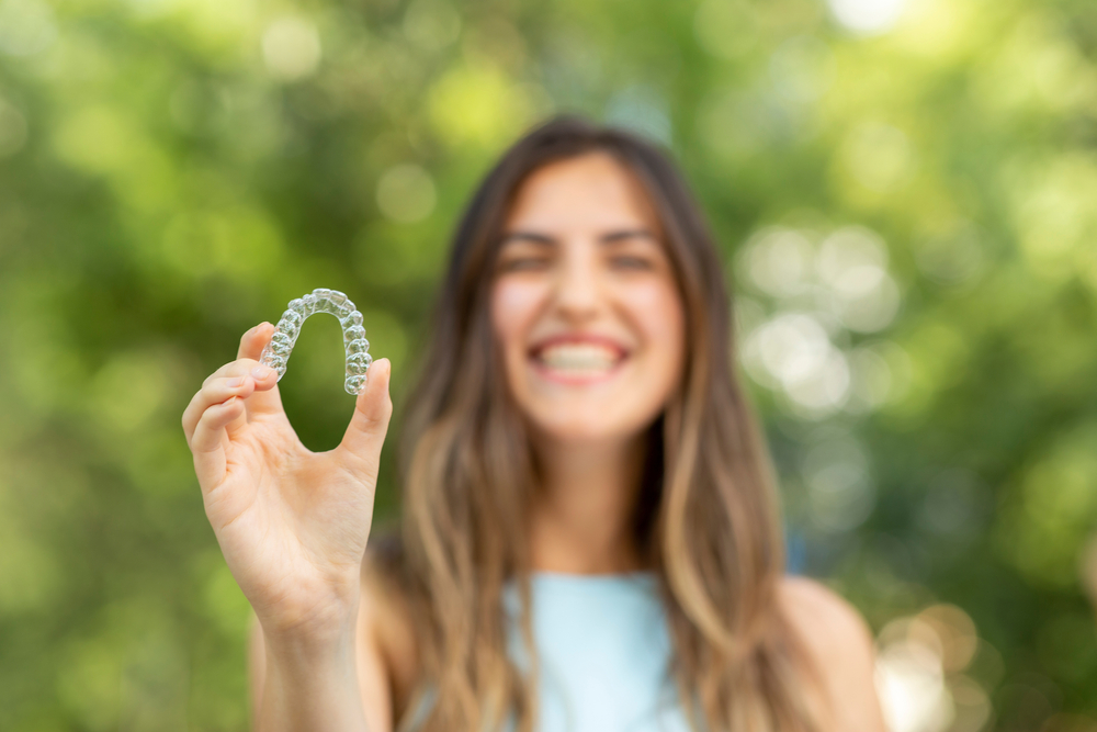 young teen holding her Invisalign aligners