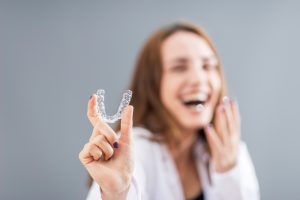 woman holding up her Invisalign aligners