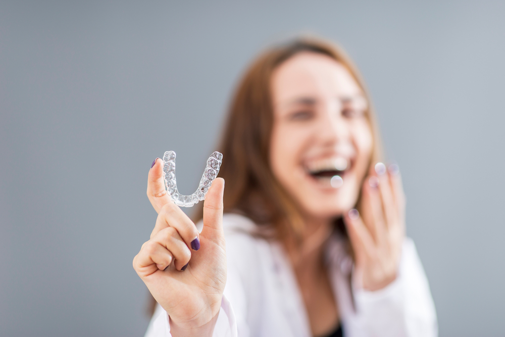 woman holding up her Invisalign aligners